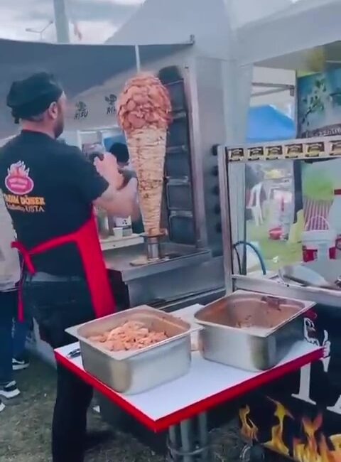 Adana'da karnavalda bir dönercinin daha pişmiş tavuğun üzerine çiğ tavuk