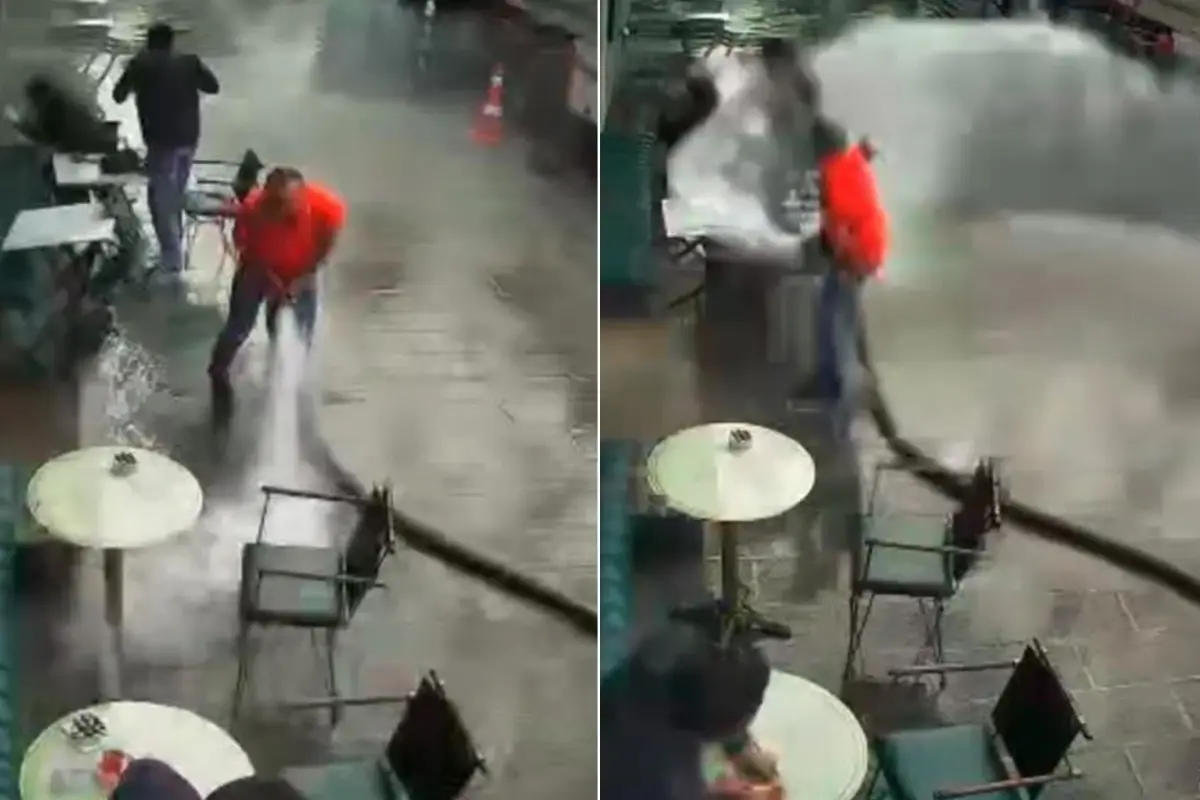 Bir kafe işletmecisi, iş yerinin önünü tazyikli suyla yıkamak isterken