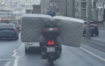 İstanbul Beylikdüzü’nde bir motosiklet sürücüsünün arkasına bağladığı yatağı trafikte taşıdığı