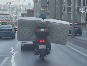 İstanbul Beylikdüzü’nde bir motosiklet sürücüsünün arkasına bağladığı yatağı trafikte taşıdığı