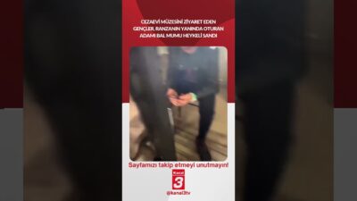 Cezaevi müzesini ziyaret eden bir grup genç, ranzanın yanında oturan